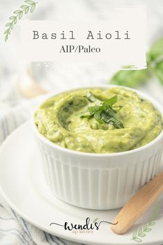 a white bowl filled with guacamole on top of a plate next to a wooden spoon