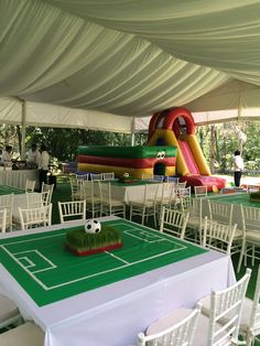 an inflatable soccer field is set up with white chairs and green tablecloths