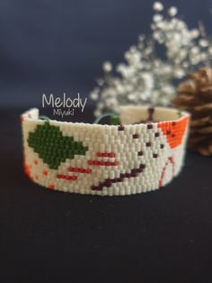 a close up of a bracelet on a table next to a pineconi tree