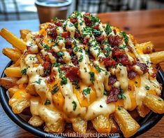 a black plate topped with cheesy fries covered in cheese and bacon toppings