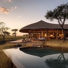 an outdoor area with a pool and gazebo in the middle of it at sunset