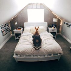 a woman laying on top of a bed in a room with white walls and lights