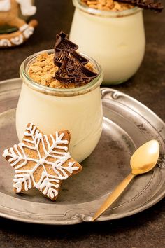 two desserts in glass jars on a silver plate with a spoon and gold spoon