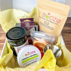 an open box containing various foods and condiments on a wooden table with yellow wrapping paper