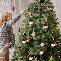 two women decorating a christmas tree with ornaments