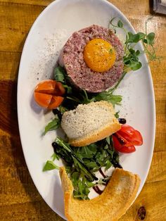 a white plate topped with meat and veggies on top of a wooden table