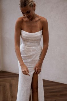 a woman in a white dress standing on a wooden floor with her legs spread out