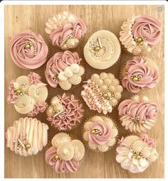 cupcakes with pink frosting and gold decorations on a wooden table, top view