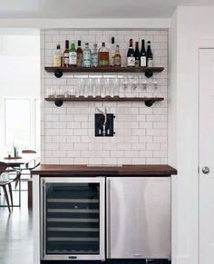 a wine cooler sitting in the middle of a kitchen next to a counter with bottles and glasses on it