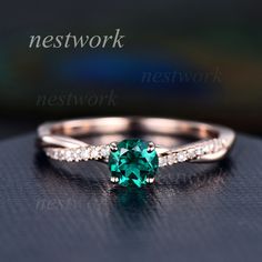 a close up view of a ring with a green stone in the middle and diamonds around it