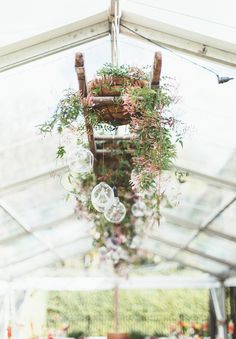 a chandelier with plants hanging from it's sides in a white tent