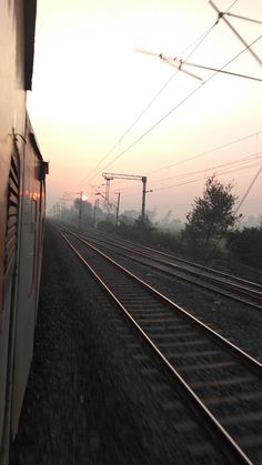 the train is traveling down the tracks in the foggy morning time, with power lines above