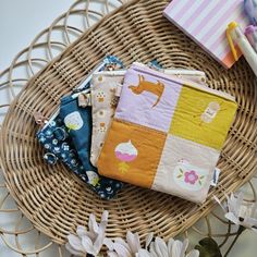 several small purses sitting on top of a wicker basket next to some flowers