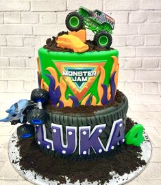 a monster truck birthday cake with dirt on the bottom and cars in the top tier