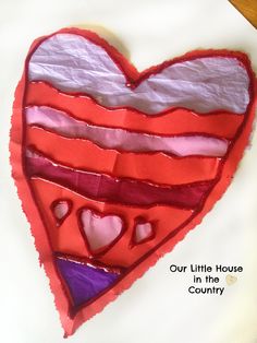 a heart made out of red, white and purple paper with hearts cut out of it