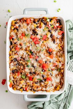 an enchilada casserole in a white dish on a green cloth