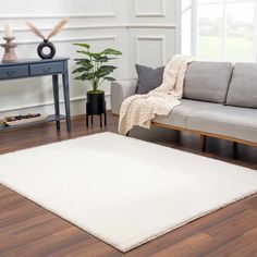 a living room with a gray couch and white rug on the floor next to a wooden table