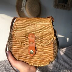 a hand holding a brown wicker purse