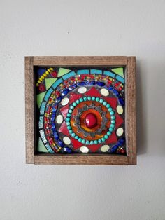 a wooden frame with a colorful glass decoration on the wall next to a white wall