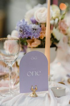 the table is set with wine glasses, candles and place cards for guests to sit at