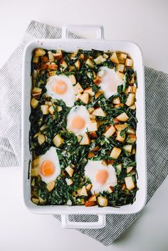 an egg and spinach casserole in a white dish on a gray towel