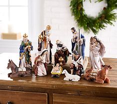 a group of figurines sitting on top of a wooden table next to a wreath