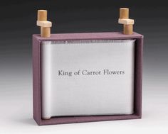 a wooden block with the words king of carrot flowers on it and two pegs sticking out of it