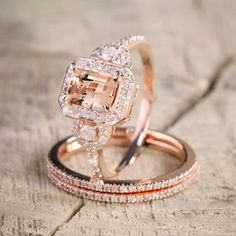 two wedding rings on top of each other sitting on a piece of wood with white and pink diamonds