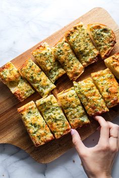 a person is pointing at some food on a cutting board that has been cut into squares