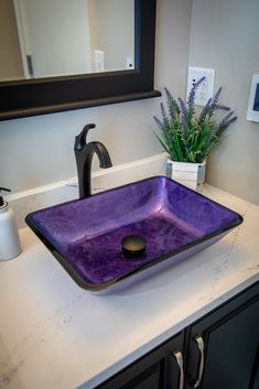 a bathroom sink that has a purple glass bowl on top of it and a black faucet