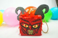 a red box with an evil face on it and balloons in the background for decoration