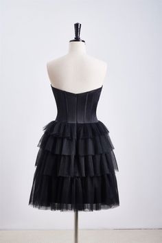 This dress features a corset bodice and a tiered ruffle skirt, with a sweetheart neck and zip-up back. Made from black tulle, it has an A-line silhouette and falls above the knee. Item #NP1112 Material: Tulle Color: Black Silhouette: A-line Embellishment: Corset bodice, tiered ruffle skirt Neck: Sweetheart neck Back: Zip-up Length: Above knee length Fully lined: Yes Built-in bra: Yes True to size. Made in China. Dresses are usually packed inside out for protection. Hand wash Tiered Corset Dress With Ruffles For Party, Tiered Ruffle Corset Dress For Party, Black Sleeveless Corset With Ruched Bodice, Black Strapless Tulle Corset Dress, Formal Corset Dress With Sweetheart Neckline And Ruffles, Cocktail Corset Dress With Ruffles And Fitted Bodice, Black Corset Dress With Ruched Bodice For Prom, Black Sweetheart Neckline Dress With Ruffles, Black Tulle Corset Dress With Lined Bodice