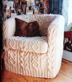 a white chair with a brown pillow on it in front of a wall full of pictures