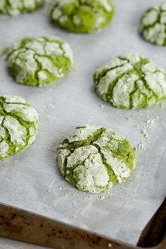 freshly baked cookies covered in powdered sugar and green icing on a baking sheet