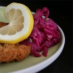 a plate with chicken, cabbage and lemon on it