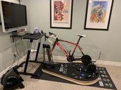 there is a bike and exercise equipment in the room with pictures on the wall behind it