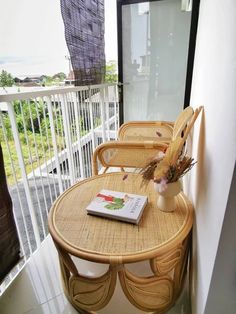 two wicker chairs sitting on top of a balcony next to a table with a book