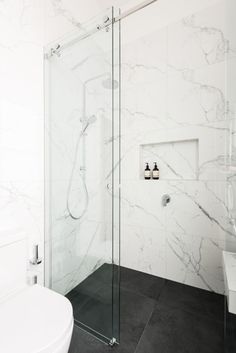 a white bathroom with marble walls and floor