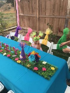 a blue table topped with flowers and grass