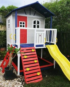 a play house with a slide and climbing frame in the back yard, next to a potted plant