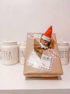 an elf's hat is on top of a brown bag and two white jars