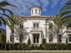 a large white house with palm trees in front