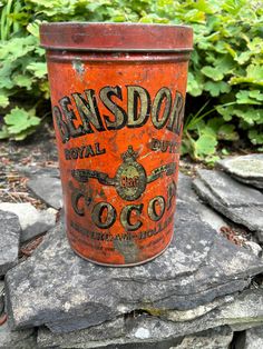 an orange tin can sitting on top of a rock