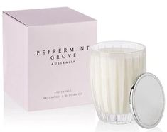 a glass candle next to a pink box on a white surface with the words peppermint grove australia