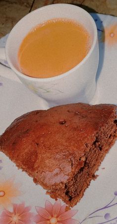 a piece of cake on a plate next to a cup of tea