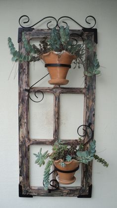 an old window frame with potted plants in it and hanging on the wall above