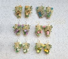 six skeleton earrings with flowers on them sitting on a white table top next to each other