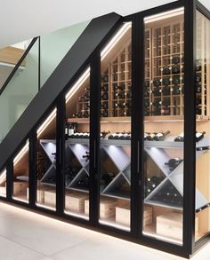 a wine cellar with many bottles in it and stairs leading up to the second floor