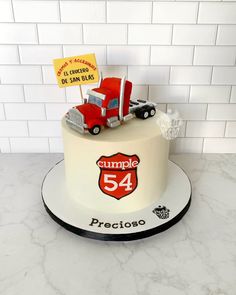 a cake with a truck on top and a sign that says cumple 54 precioso