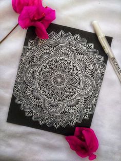 a black and white drawing with pink flowers next to it on a sheet of paper